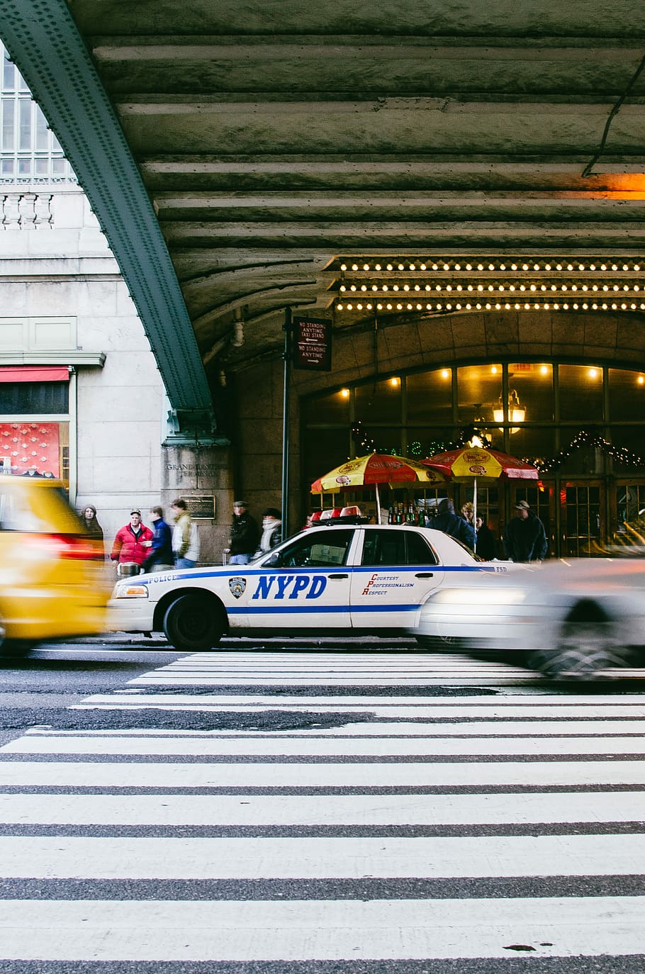 time-lapse photography of NYPD police car at pedestrian lane, NYPD Ford Crown Victoria near near taxi under grey bridge