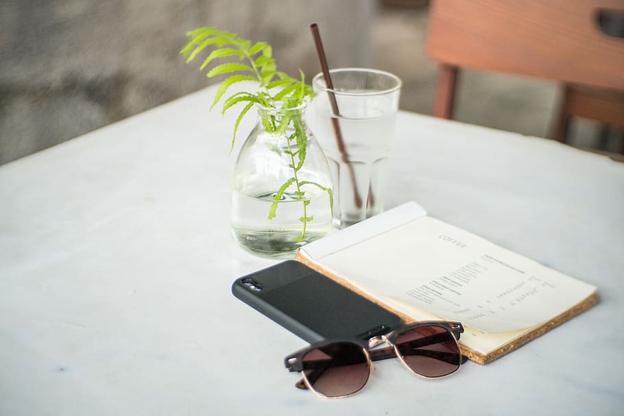 black framed sunglasses beside black cased smartphone and white covered book on white table, black Clubmaster-framed sunglasses beside book on white tablecloth HD wallpaper
