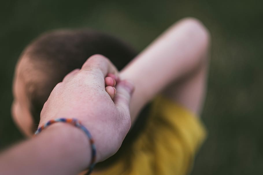 close-up photography of hands, person holding his child's hand