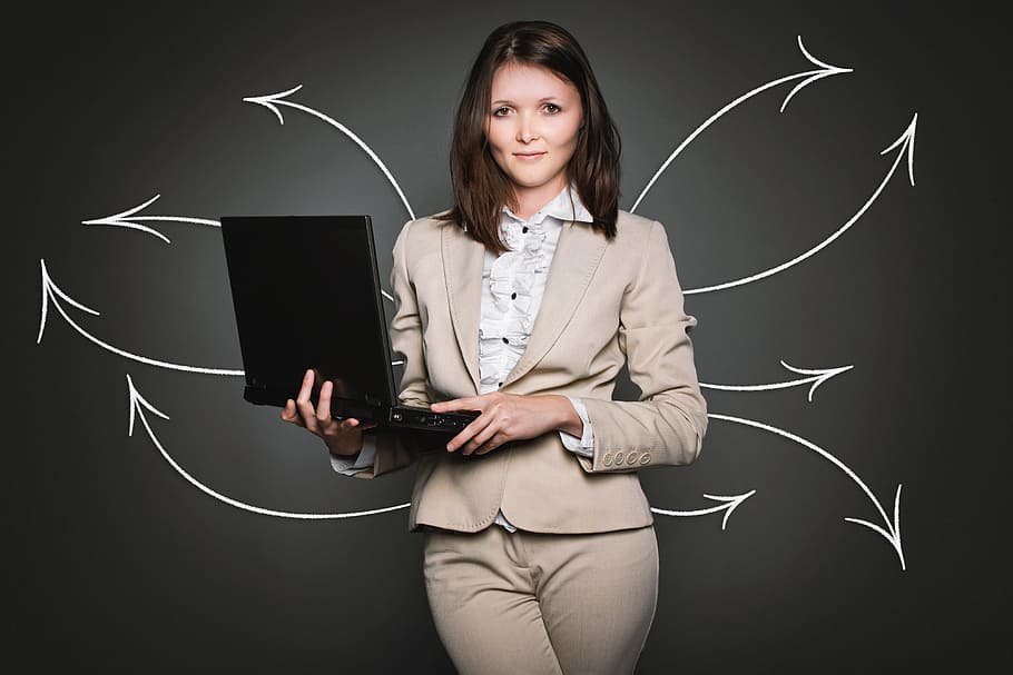 woman wearing grey blazer and grey bottoms smiling while holding laptop computer HD wallpaper