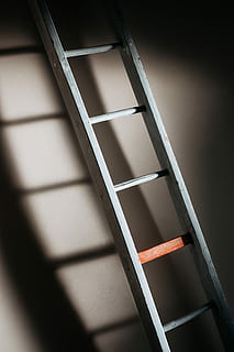 An old wooden ladder casting soft shadows on wall, white step ladder lean on wall with shadow HD wallpaper