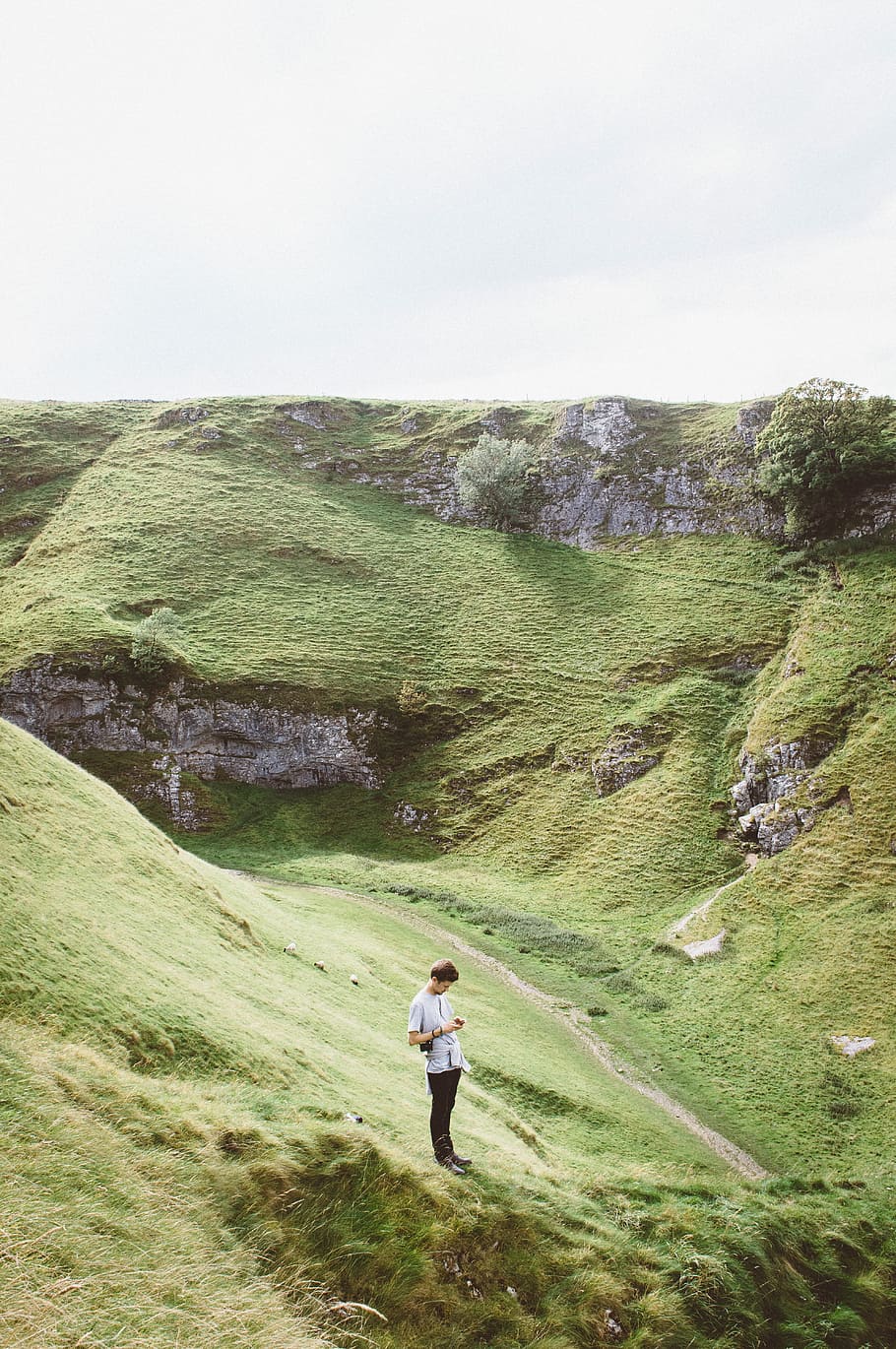 man standing on green grass on mountain, aerial photography of man standing near valley HD wallpaper