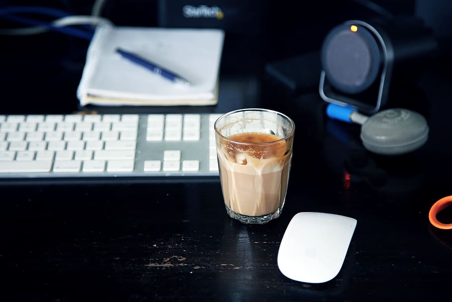 clear glass shot glass beside Apple Magic Mouse, clear drinking glass filled with brown liquid near Apple machine keyboard and mouse HD wallpaper