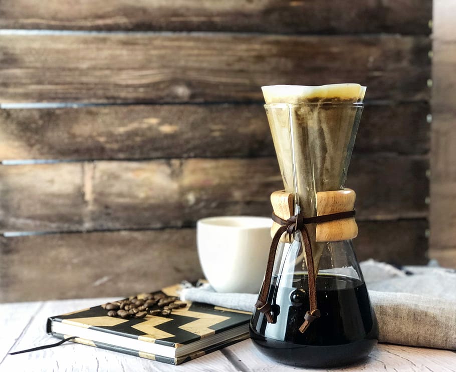 clear glass pitcher beside book, photo of drip coffee bottle beside notebook
