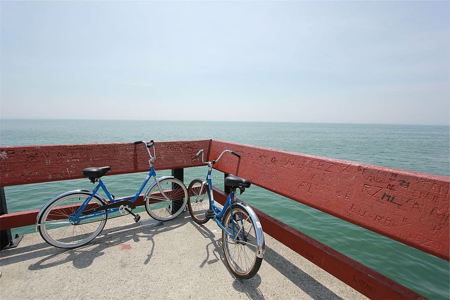 two cruiser bikes parked beside wooden fence overlooking body of water HD wallpaper
