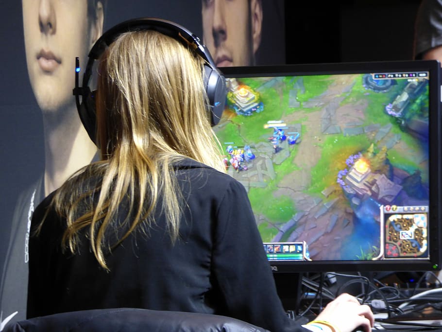 woman wearing black long sleeve top in front of computer monitor playing League of Legends