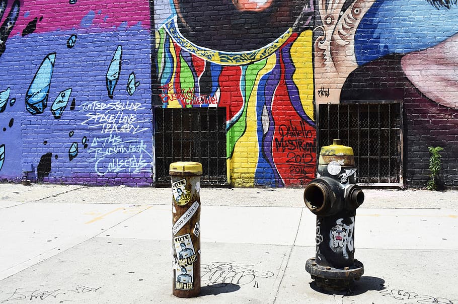 black fire hydrant near graffiti wall, black fire hydrant on sidewalk perpendicular to mural wall