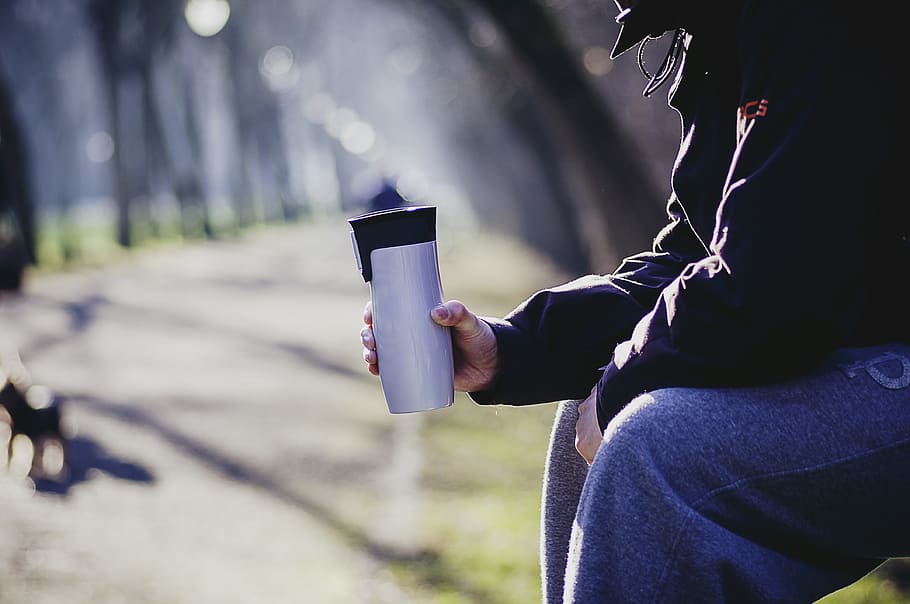 selective focus photography of man sitting on bench holding tumbler, HD wallpaper