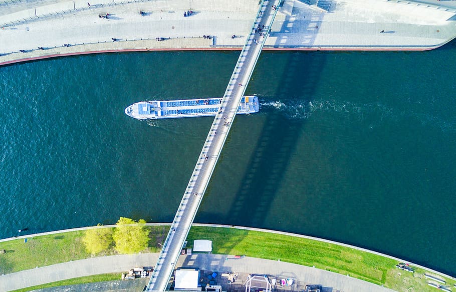 aerial photography of white boat passing under white bridge, top view photography of boat on body of water under bridge HD wallpaper