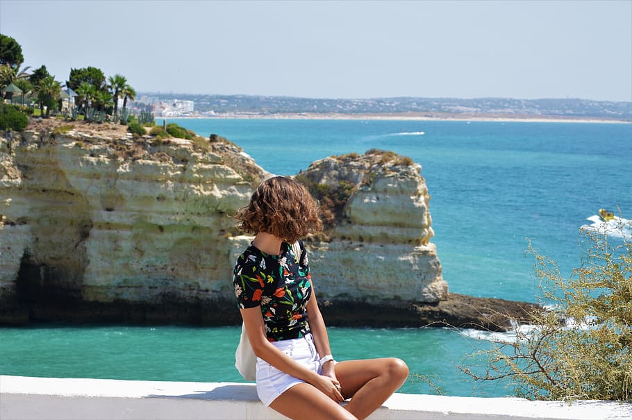 woman sitting on white rock formation near beach, sea, ocean