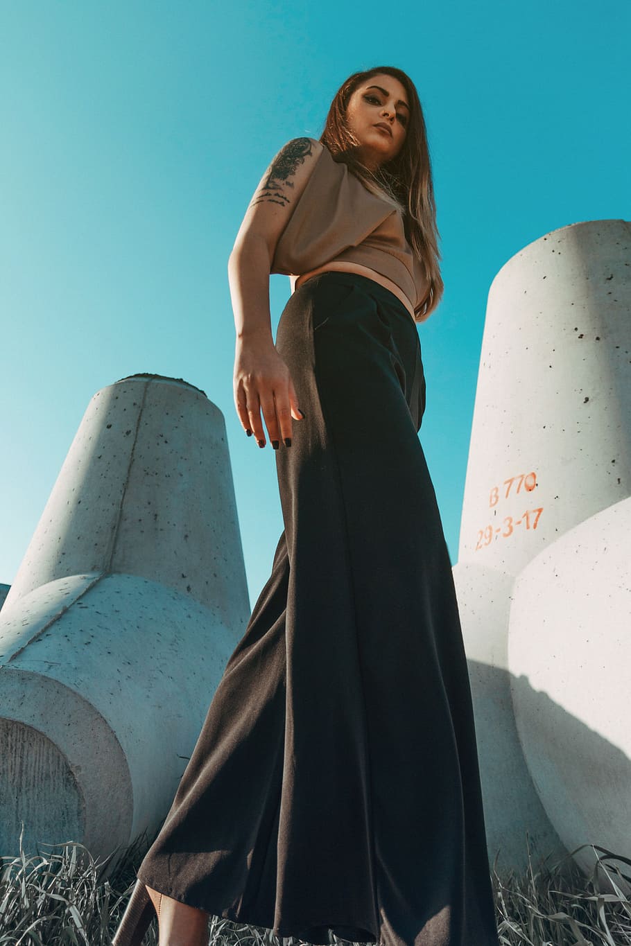 brown haired woman in brown top and black maxi skirt standing near concrete wall HD wallpaper