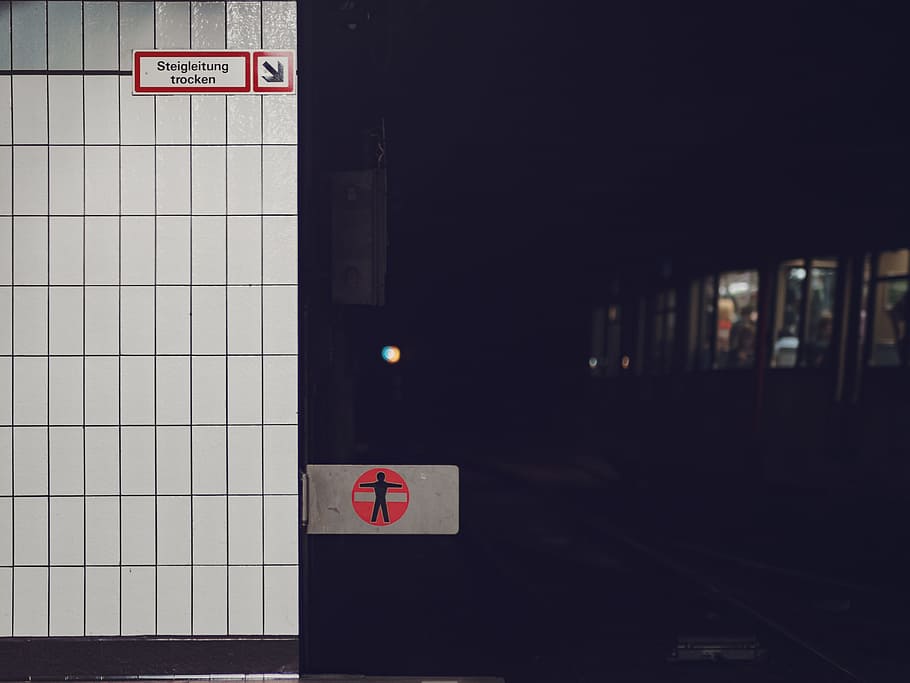 Subway train in a dark underground train station near a tiled wall with a warning sign, untitled HD wallpaper
