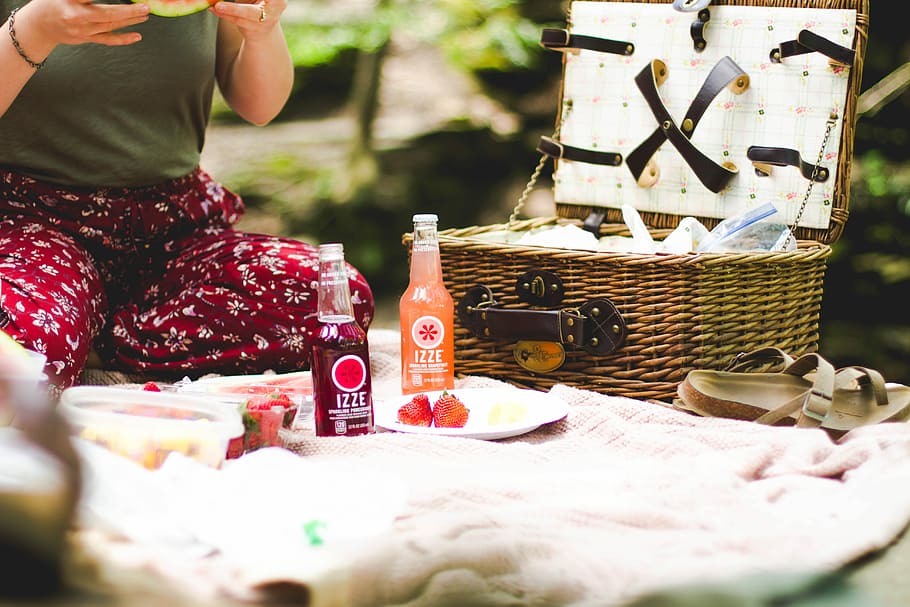 picnic basket beside two Ezze bottles on blanket, two bottles near picnic basket