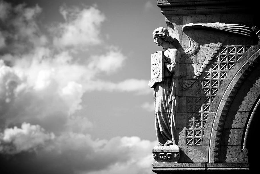 greyscale photo of angel statue sculpted on building, europe