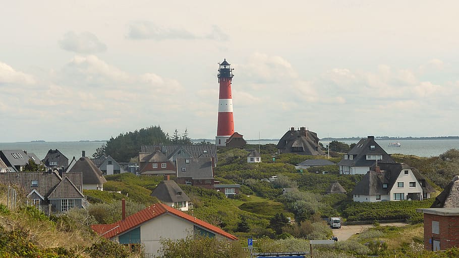 red and white lighthouse near houses during daytime, island end