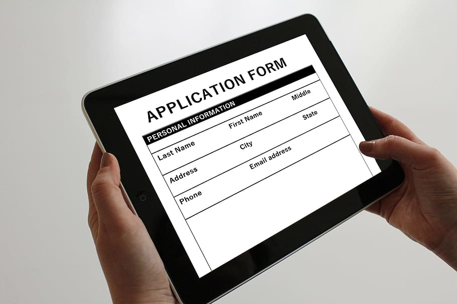 person holding tablet displaying application form, tablet computer