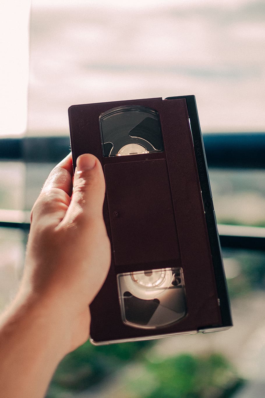 person holding black VHS tape, person holding VHS tape, bedroom