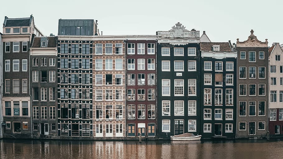 concrete buildings beside body of water, river beside the buildings during daytime HD wallpaper