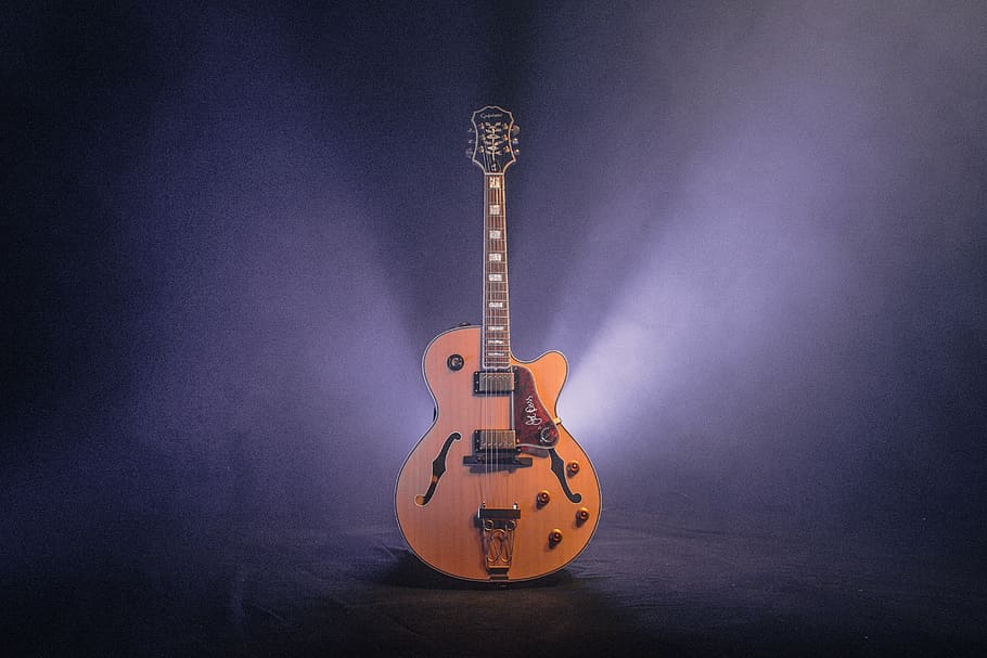 brown and black jazz guitar with dim light, photography of jazz guitar