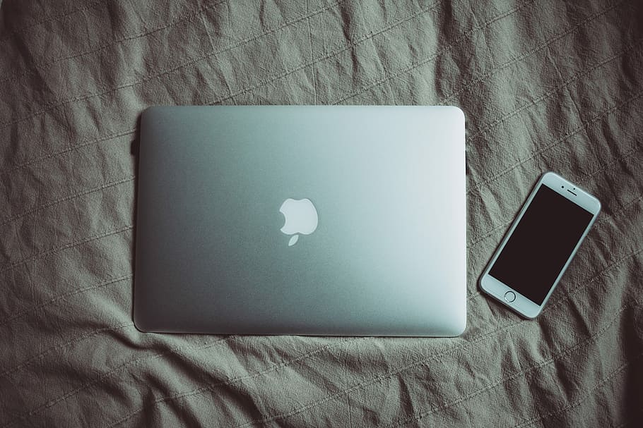 silver MacBook beside post-2014 iPhone, silver MacBook on top of brown textile HD wallpaper