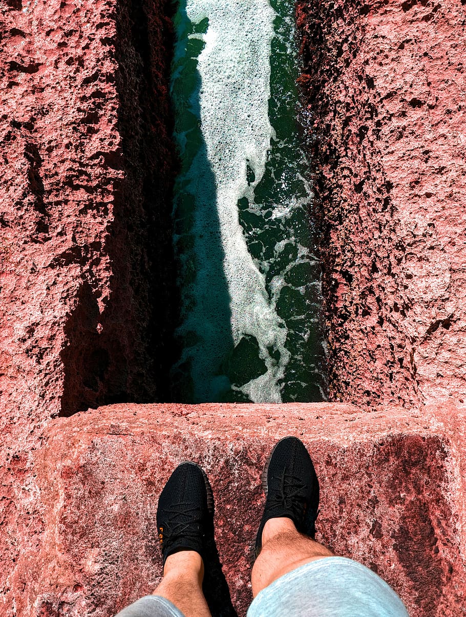 high angle photo of water, person standing on cliff above body of water HD wallpaper