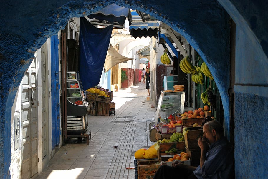 man leaning on wall beside his fruit stand in an alley, Morocco, HD wallpaper