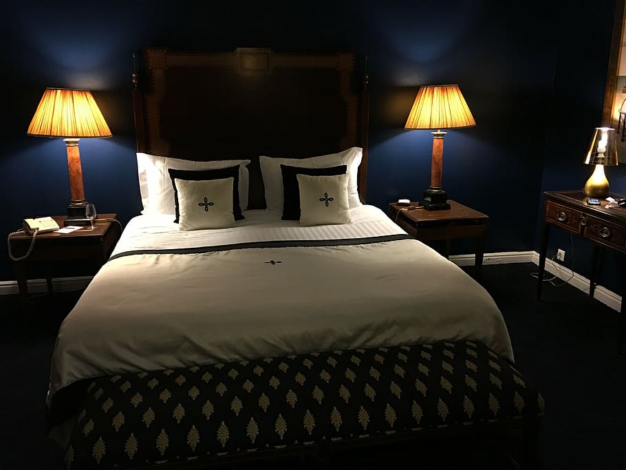 person taking photo of bedroom with table lamp turned on, hotel room