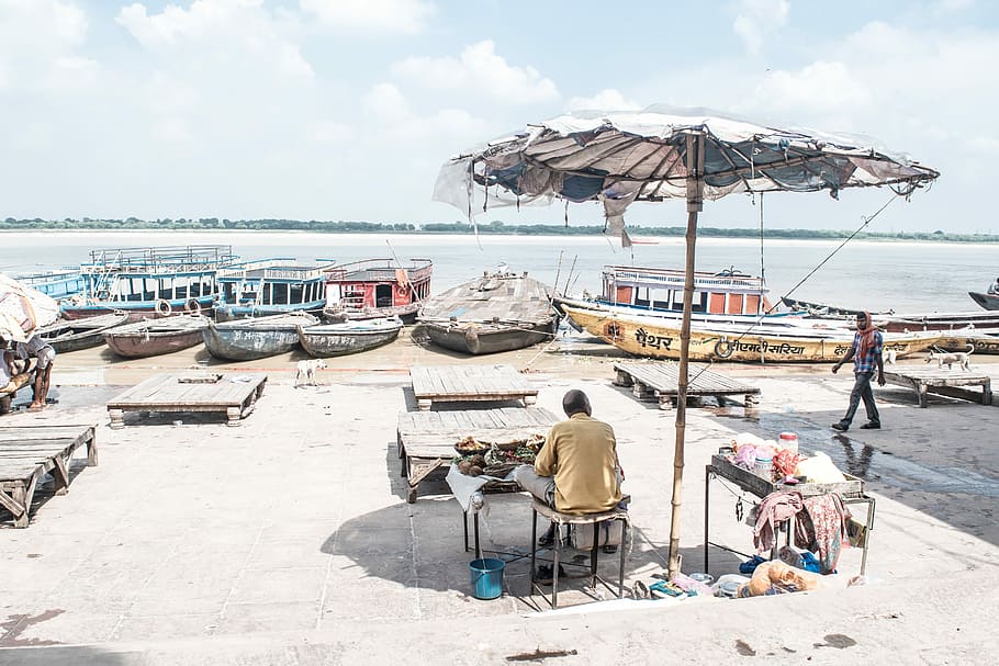 photo of man under patio umbrella near body of water, man sitting on chair near on bay near body of water HD wallpaper