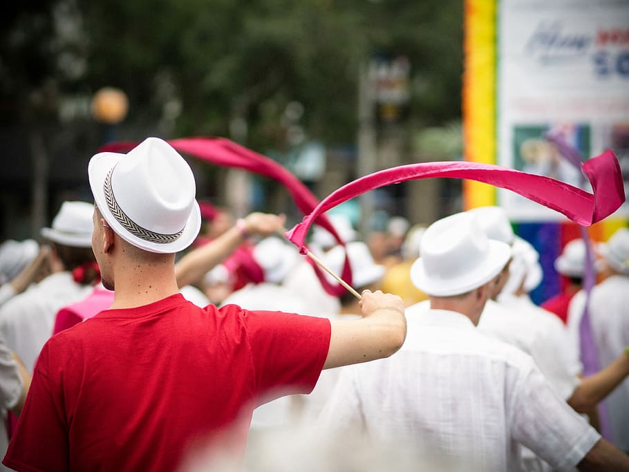 man in red crew-neck T-shirt and white hat holding stick with red lace HD wallpaper