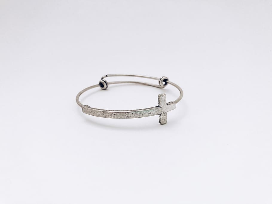 closeup photo of silver-colored cross bangle, silver-colored tension bracelet