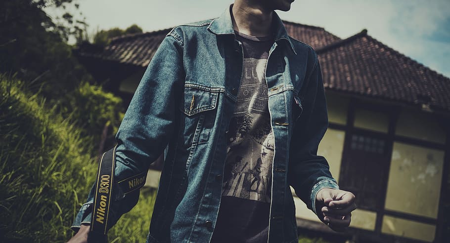 person in blue denim button-up shirt carrying black Nikon camera HD wallpaper