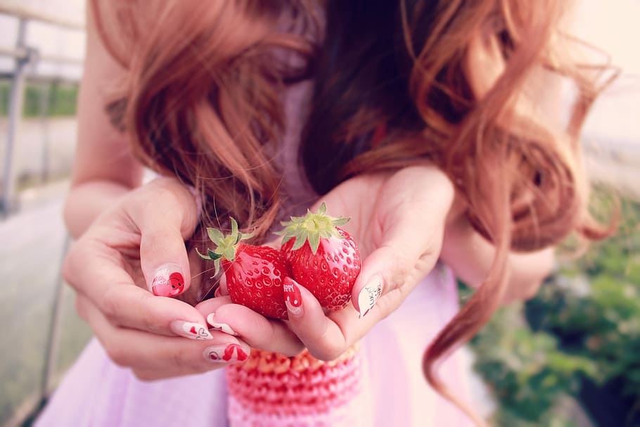 selective focus photography of a woman holding two strawberries HD wallpaper