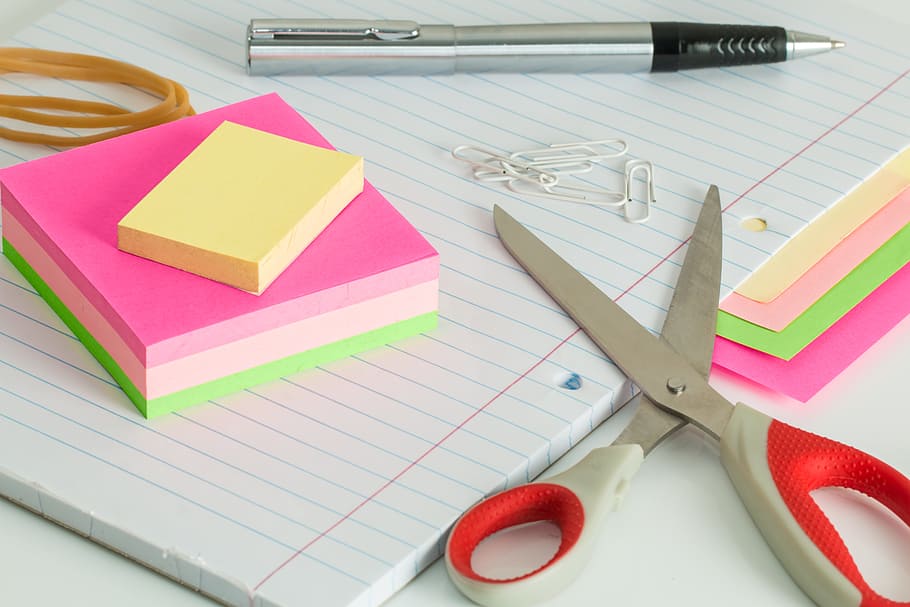 scissors near note pad, post it notes, desk, clutter, pen, elastic bands