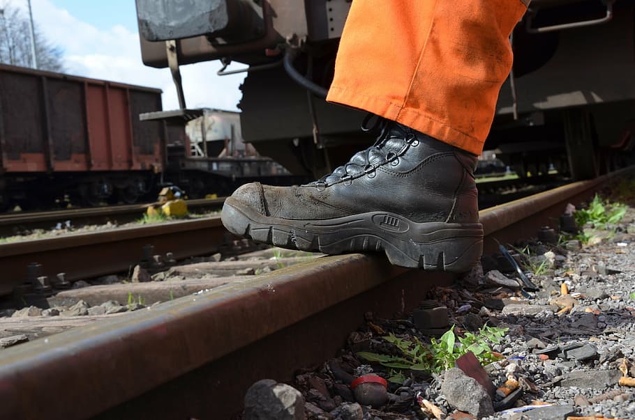 person wearing black leather combat boot stepping on train track, HD wallpaper