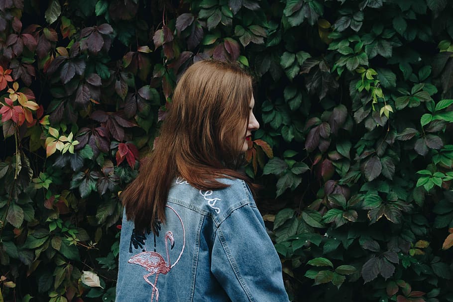 woman standing front of green and multicolored leafed plants, woman in blue denim jacket HD wallpaper