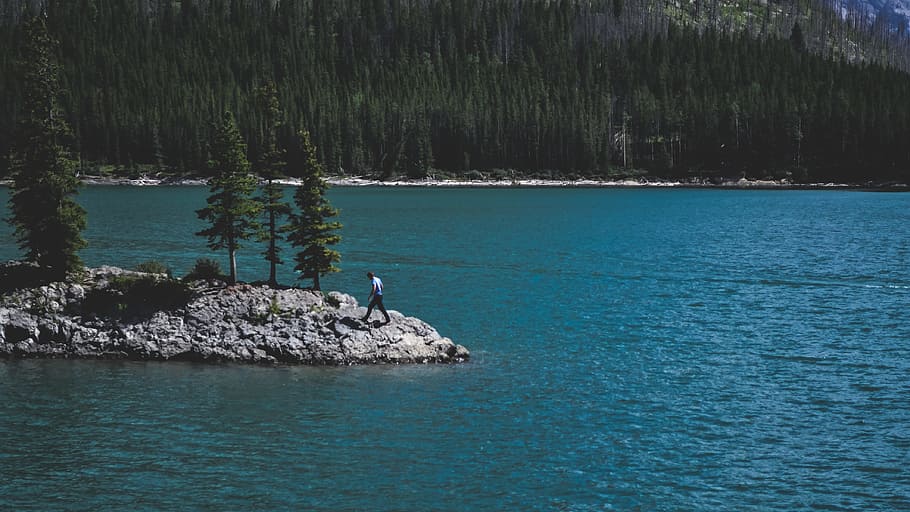 person walking on rock beside body of water, person near body of water near island HD wallpaper