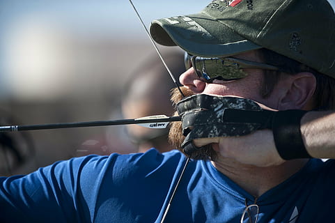 man wearing green fitted cap holding black and white bow, archery HD wallpaper