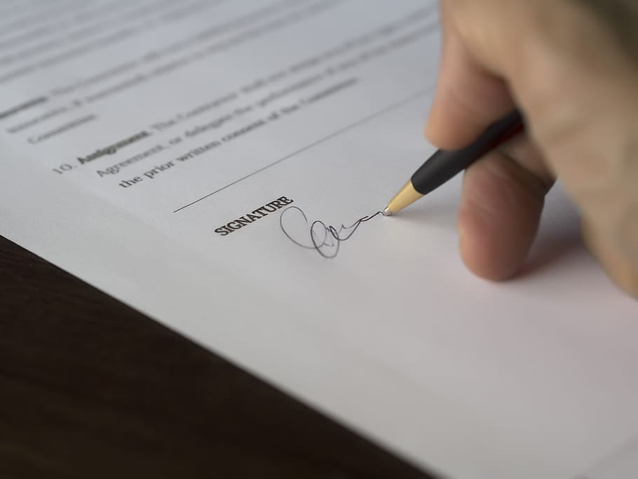 person signing a paper with black pen close up photo, business
