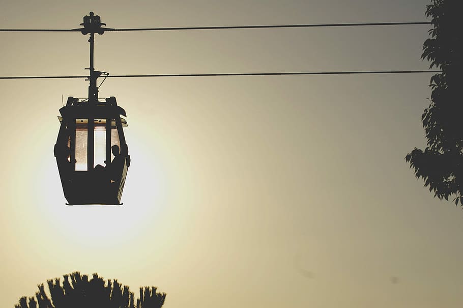 black ski lift, person sitting in cable car silhouette during golden hour HD wallpaper