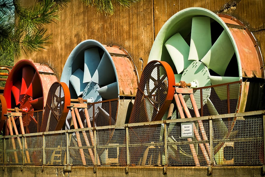 three red, blue, and green windmills near brown wooden wall, architecture