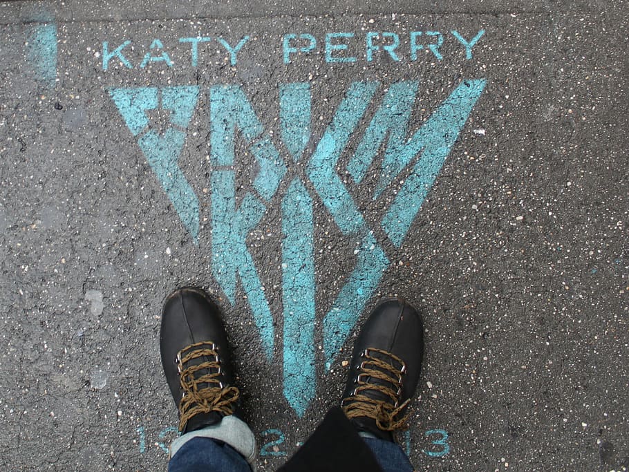 person wearing black leather shoes standing on gray pavement with blue Katy Perry print HD wallpaper