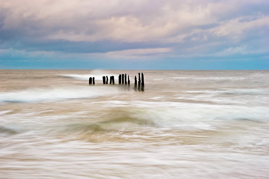 time-lapse photography of brown dock, sea wave crashing at standing stones HD wallpaper