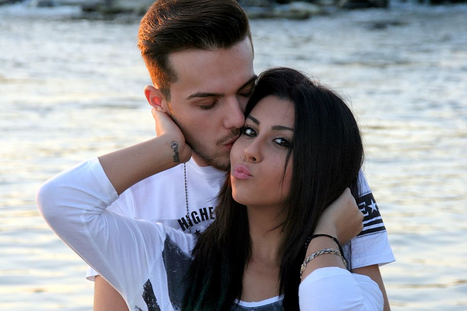 man kissing woman standing near body of water, couple, love, beauty