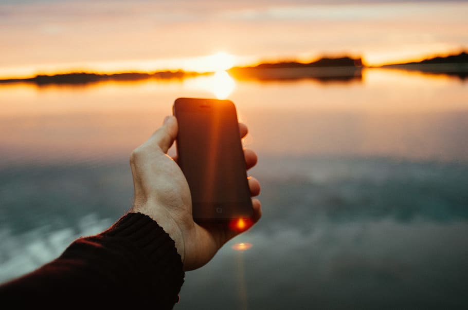 person holding black iPhone near lake during sunset, person holding black iPhone 5, HD wallpaper