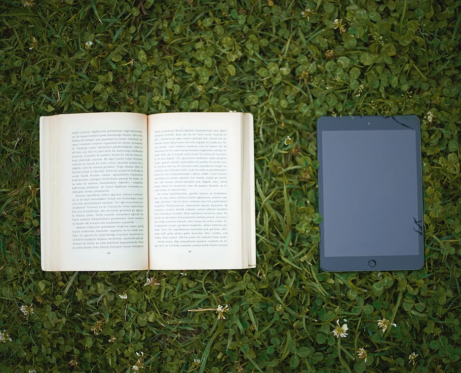 black iPad beside beige book on green grass, read, technology HD wallpaper