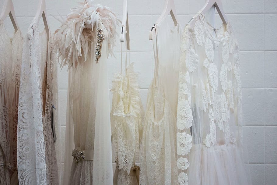 hanged beige and white dresses near white wall, wardrobe, closet