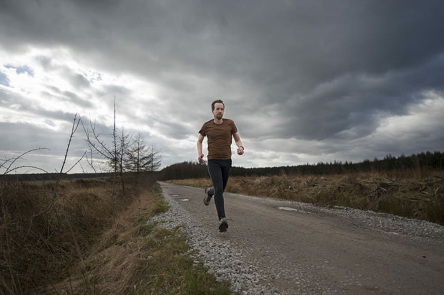 man running at the road during daytime, man running between hay field under cloudy sky during daytime HD wallpaper