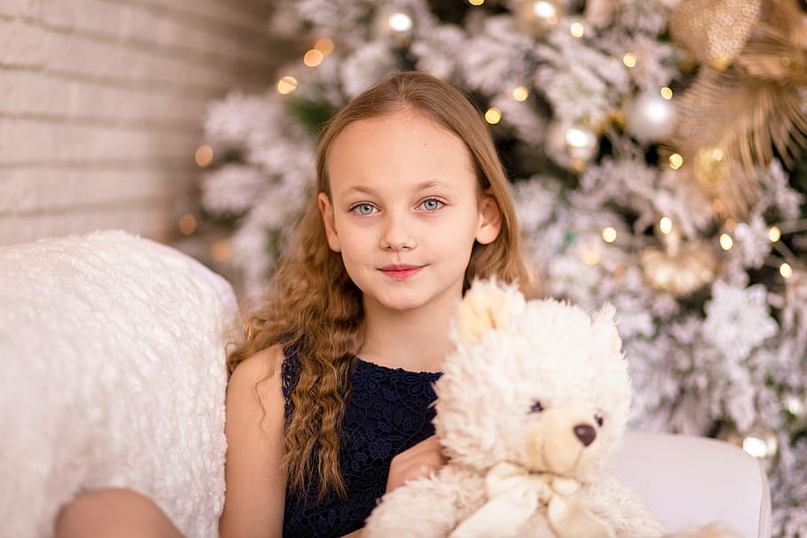 girl holding white bear plush toy sitting on sofa, child, kid