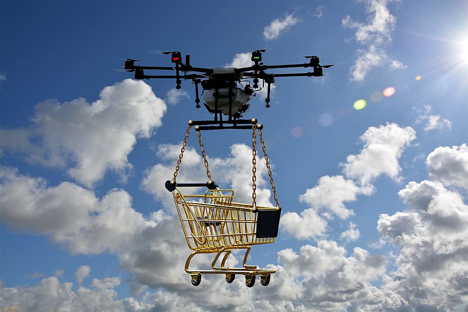 white and black drone lifting yellow shopping cart during daytime