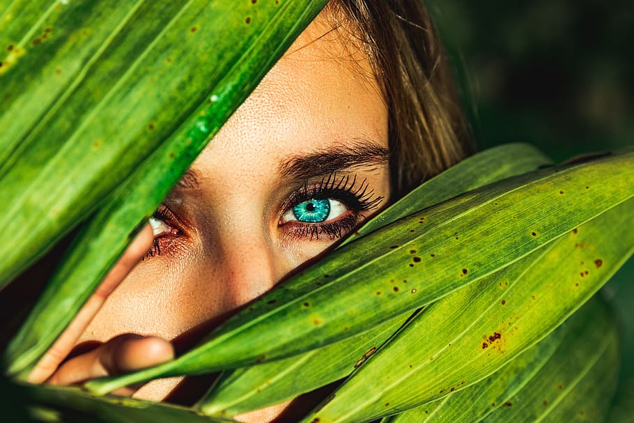 woman behind green leaves, woman peeping in covered by palm leaves